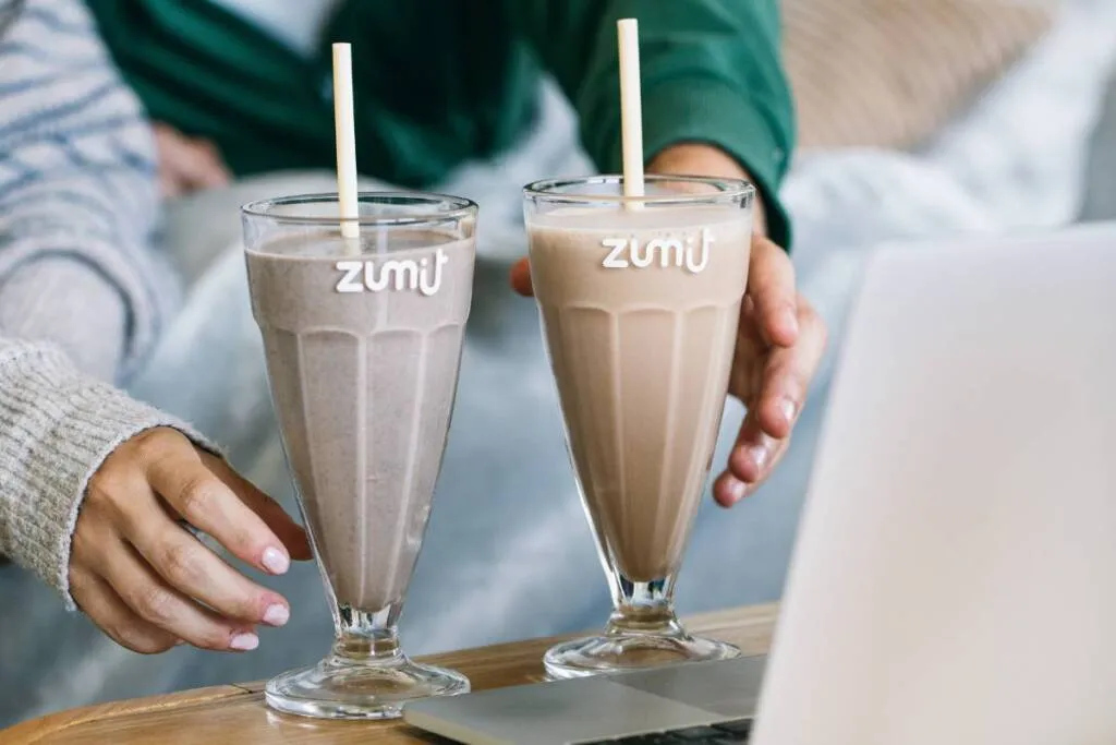 Milkshakes Zumit com a tecnologia IQF nas mãos das pessoas, numa mesa, nas mãos das pessoas, numa mesa.
