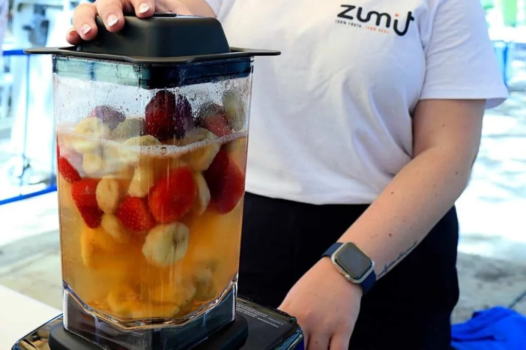 mezclas de fruta congelada en la trituradora con zumo de manzana