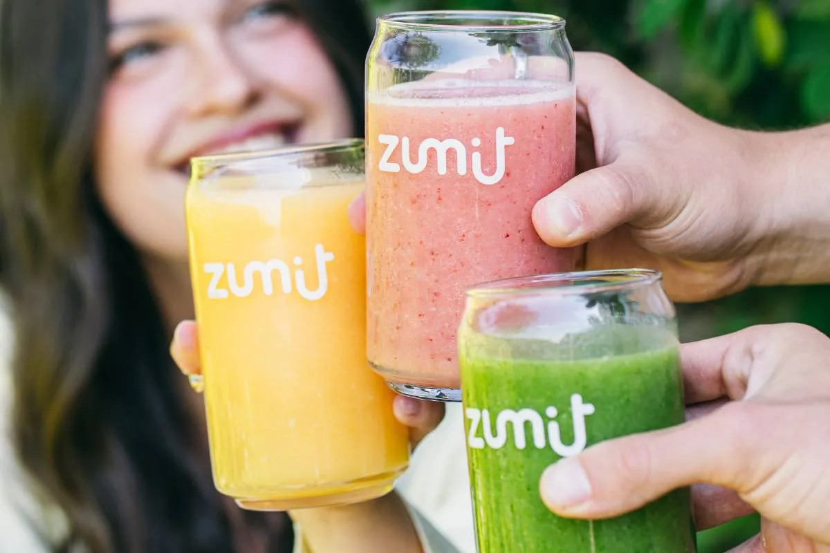 Smoothies Zumit con tecnología IQF en manos de personas sonriendo