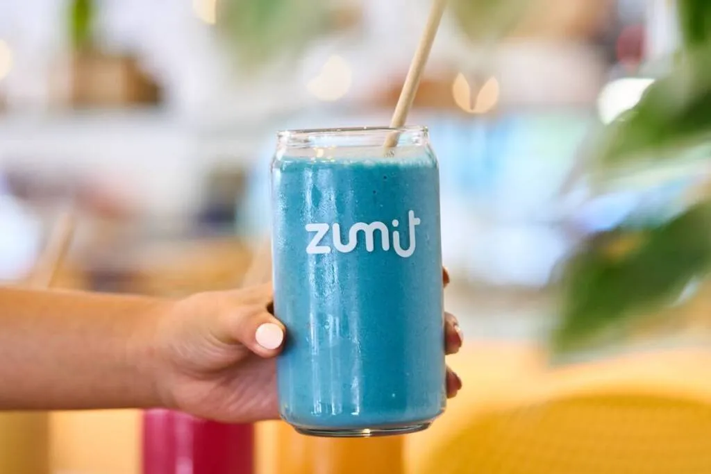 Smoothie banana, manga, pêssego, ananás, leite de coco e espirulina azul, ideal para pequenos-almoços energéticos e equilibrados.