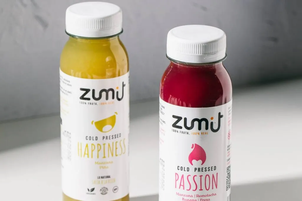 Sucos Cold Pressed Zumit Happiness e Passion, sobre uma mesa.